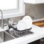 Umbra Sinkin Dish Rack 3-In-1  - Black and Nickel in use next to the sink with dishes