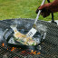 Le Creuset Outdoor Stainless Steel Slotted Turner Spatula turning fish in a grilling basket