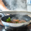 KitchenCraft Wire Splatter Screen - 28cm on a steamy pan with food