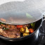 KitchenCraft Wire Splatter Screen - 28cm on a steamy pan with food