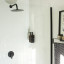 Joon Matte Black Adjustable Dispenser with Amber Bottle - Double on a wall in the shower