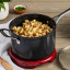 Le Creuset Essential Non-Stick Ceramic Saucepan with Glass Lid - 16cm with food on the table