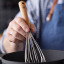 HOLM Stainless Steel Whisk with Acacia Wood Handle in a bowl