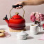 Le Creuset Classic Whistling Stovetop Kettle with Heart Knob, 1.6L - Cerise on the table with tea cups