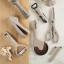Fusion Twist Multi Peeler - Grey on the table with other kitchen tools