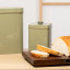 Artisan Street Embossed Storage Canister - Green on the counter with sliced bread