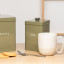 Artisan Street Tea Storage Canister - Green with a cup of tea on the table