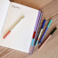 Kikkerland Metal Barrel Ballpoint Pens, Set of 4 with a book on the table