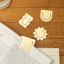 Kikkerland 3-in-1 Metal Paperclips on the table with an opened book