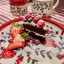 Humble & Mash Pomegranate Ceramic Platter, 25cm on a table with a slice of cake