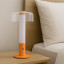 Arc & Hue Arcis Portable & Rechargeable LED Lamp - Orange on a nightstand 