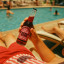 Doubleshot Coffee & Tea Cherry Bomb Soda, Pack of 6 being held next to a pool