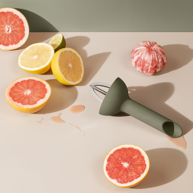 Eva Solo Green Tool Citrus Press on the kitchen counter with citrus fruits