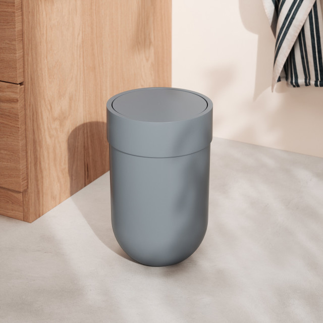 Umbra Touch Bin with Flip-Top Lid, 6L - Slate Blue next to a cupboard