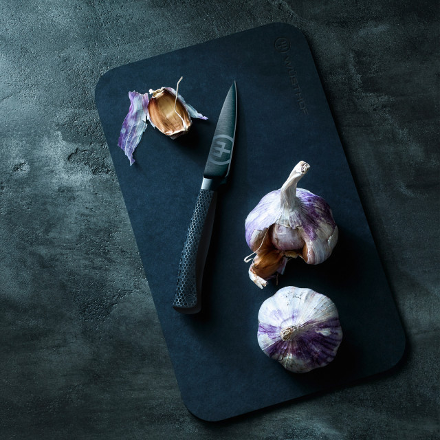 WÃ¼sthof Performer Paring Knife, 9cm on a chopping board next to garlic