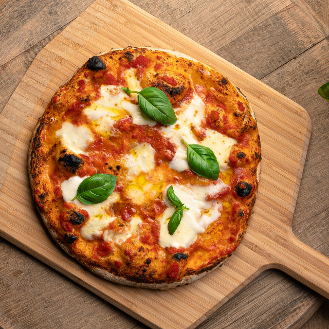Ooni Bamboo Serving Peel, 30cm with pizza on the table