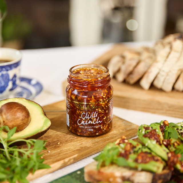 Delish Sisters Chilli Crunch on the table with bread and avocado