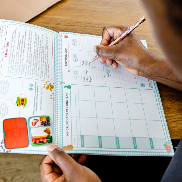 Crunchbox Menu Planner on the table writing a meal plan