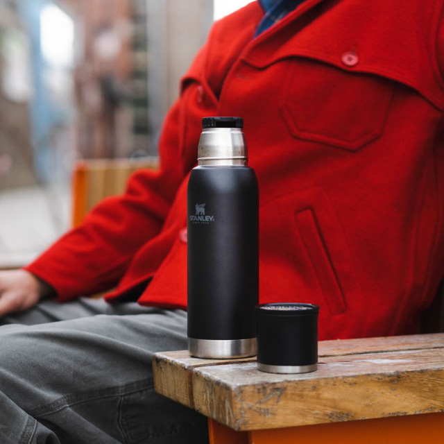 Stanley The Adventure To-Go Bottle, 740ml - Black on the wooden char arm rest