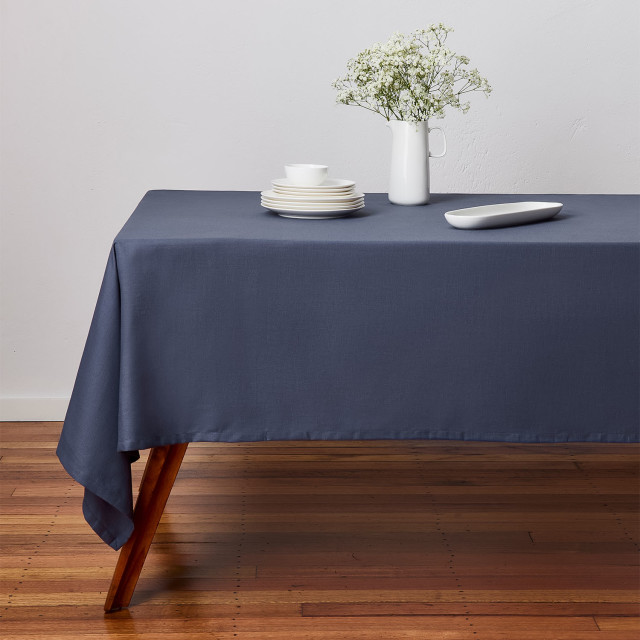 Maxwell & Williams Cotton Classics Rectangular Tablecloth, 3m - Denim on the table with a dinner set and a flower pot
