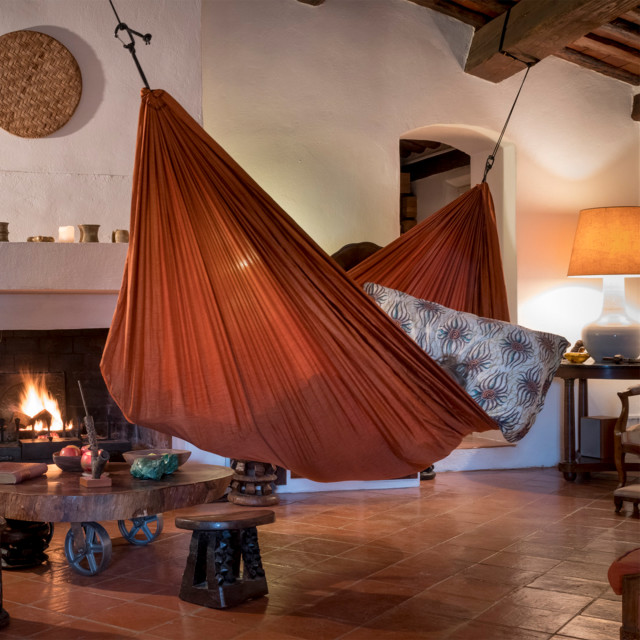 Ticket To The Moon Large Home Hammock - Terracotta Orange next to a fireplace