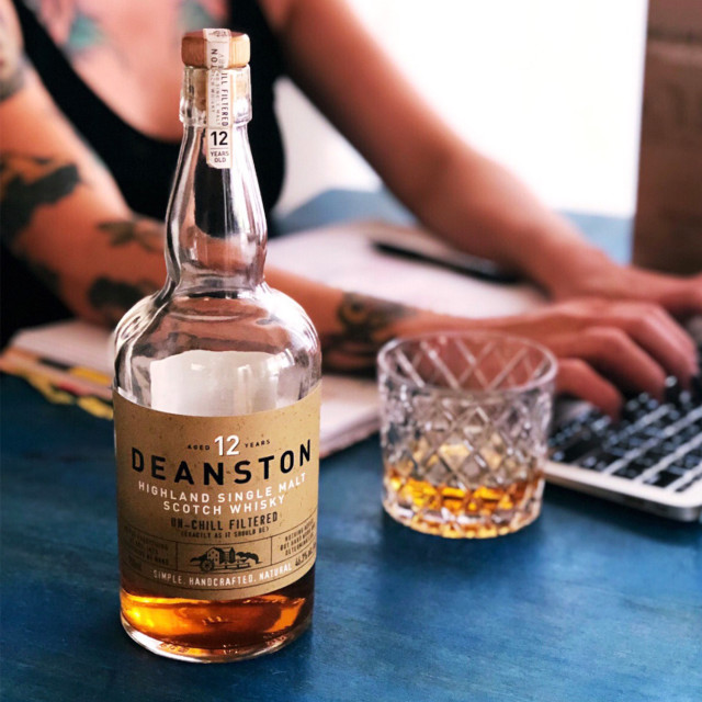 Deanston 12-Year-Old Single Malt Scotch Whisky, 700ml on the table with a laptop