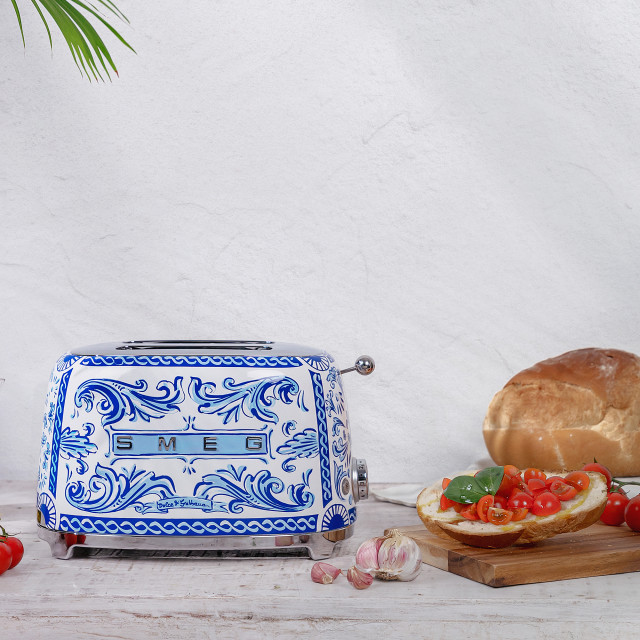 Smeg Blu Mediterraneo Dolce & Gabanna 2-Slice Toaster, 950W In a kitchen setting with toasted bread and tomato