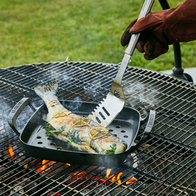 Le Creuset Outdoor Stainless Steel Slotted Turner Spatula turning fish in a grilling basket