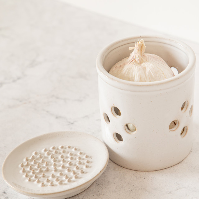 KitchenCraft Idilica Stoneware Garlic Storage Jar with a Grater Lid with garlic on the table