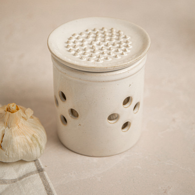 KitchenCraft Idilica Stoneware Garlic Storage Jar with a Grater Lid with garlic on the table