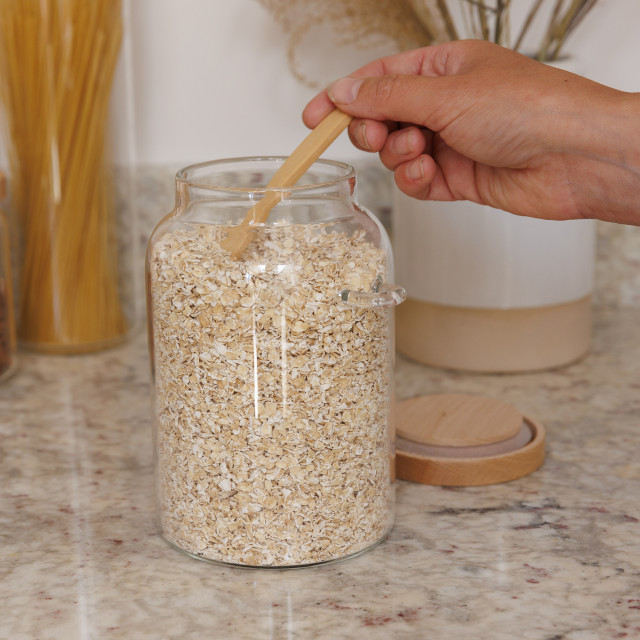 KitchenCraft Idilica Glass Storage Jar with Beechwood Lid and Bamboo Spoon on the table