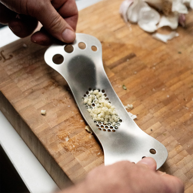 Tala Garlic Rocker and Herb Stripper in use with garlic
