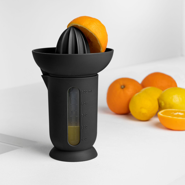 Blim Plus UFO Juicer with QB Jug - Carbon Black on the table with oranges