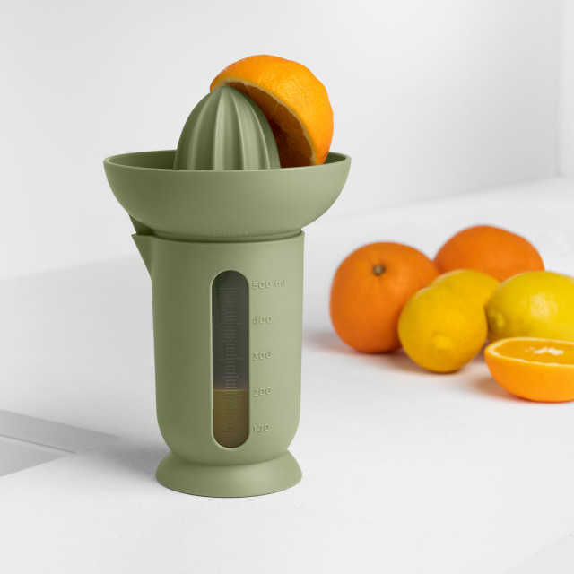 Blim Plus UFO Juicer with QB Jug - Forest Dark on the table with oranges