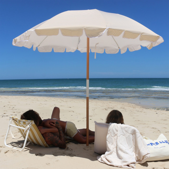 Sunnylife Beach Umbrella - Mango Bay Golden Mustard Stripe at the beach