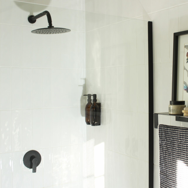 Joon Matte Black Adjustable Dispenser with Amber Bottle - Double on a wall in the shower