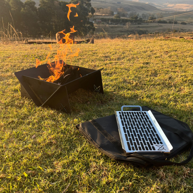 Pretzel Fire Pit with Carrier Bag and Grill - Black & Stainless Steel with fire on grass