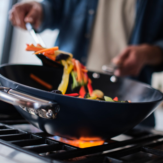 Joseph Joseph Space Ceramic Non-Stick Blue Wok with Folding Handle, 32cm on the stove with stir fry