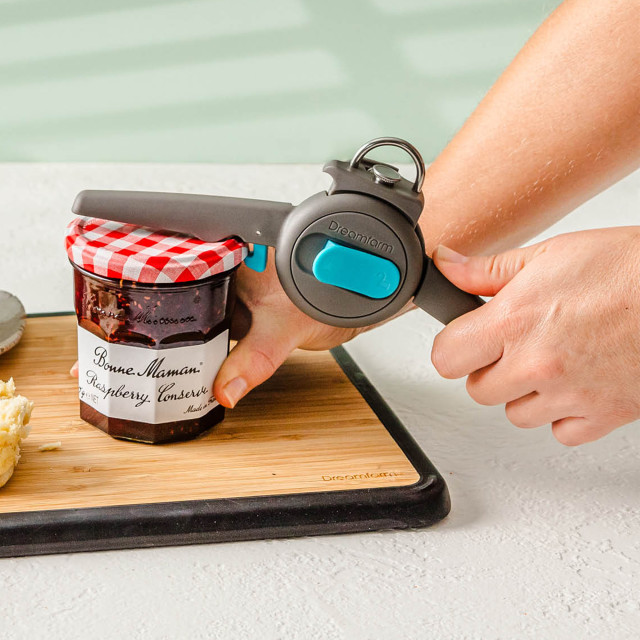 Dreamfarm Dopener 3-in-1 Ergonomic Can Opener opening a can on a chopping board