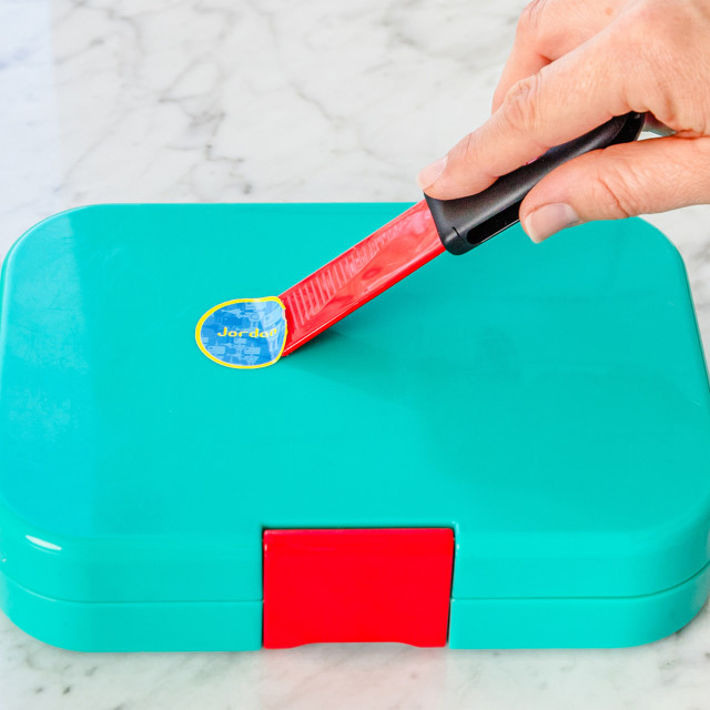 Dreamfarm Self Sharpening Cleaning Scrapers, Set of 2 removing a sticker on a lunchbox