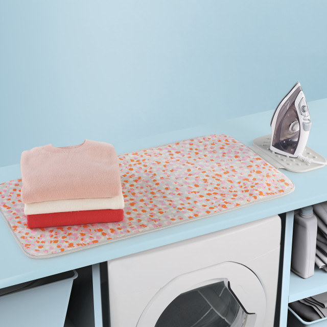 Joseph Joseph Swift Ironing Mat - Peach Blossom with folded clothes and an iron