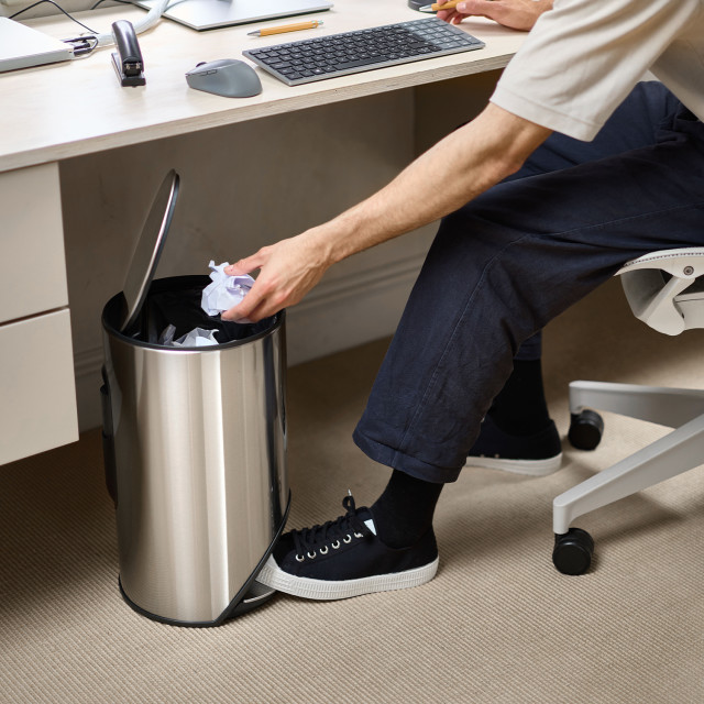 Joseph Joseph Arc 10L Pedal Bin - Stainless Steel next to a desk