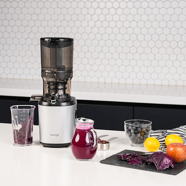 Kuvings Auto6 Cold Press Juicer - White Silver on the table with fruit juice