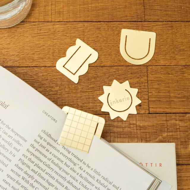Kikkerland 3-in-1 Metal Paperclips on the table with an opened book