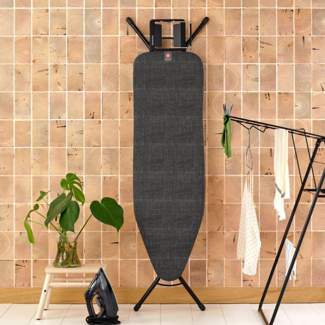 Brabantia Denim Black Ironing Board with Steam Iron Rest, 124cm x 38cm against a wall