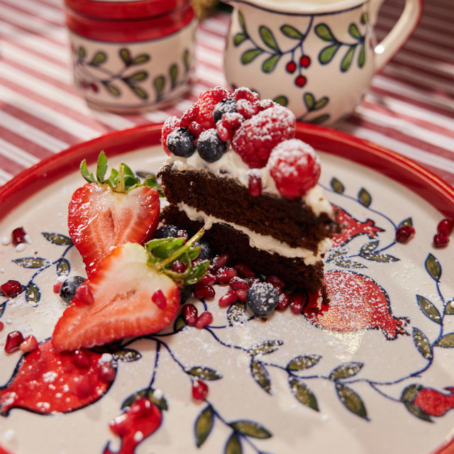 Humble & Mash Pomegranate Ceramic Platter, 25cm on a table with a slice of cake