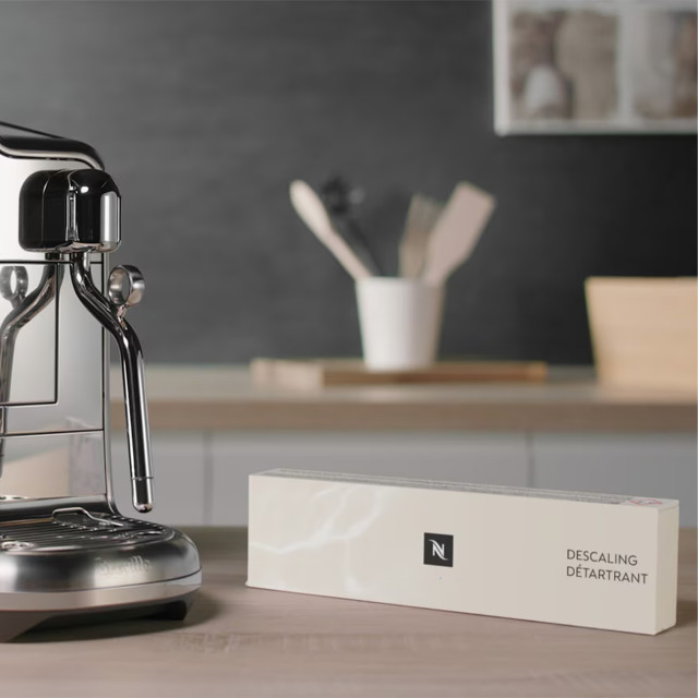 Nespresso Descaling Kit, Set of 2 next to a coffee machine