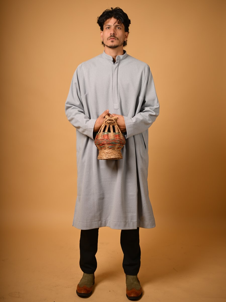 A Kashmiri man in a pheran holding a kangri.