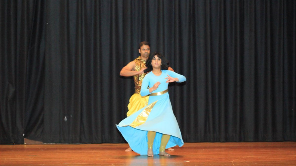 A classical dance duo performing in blue and gold costumes