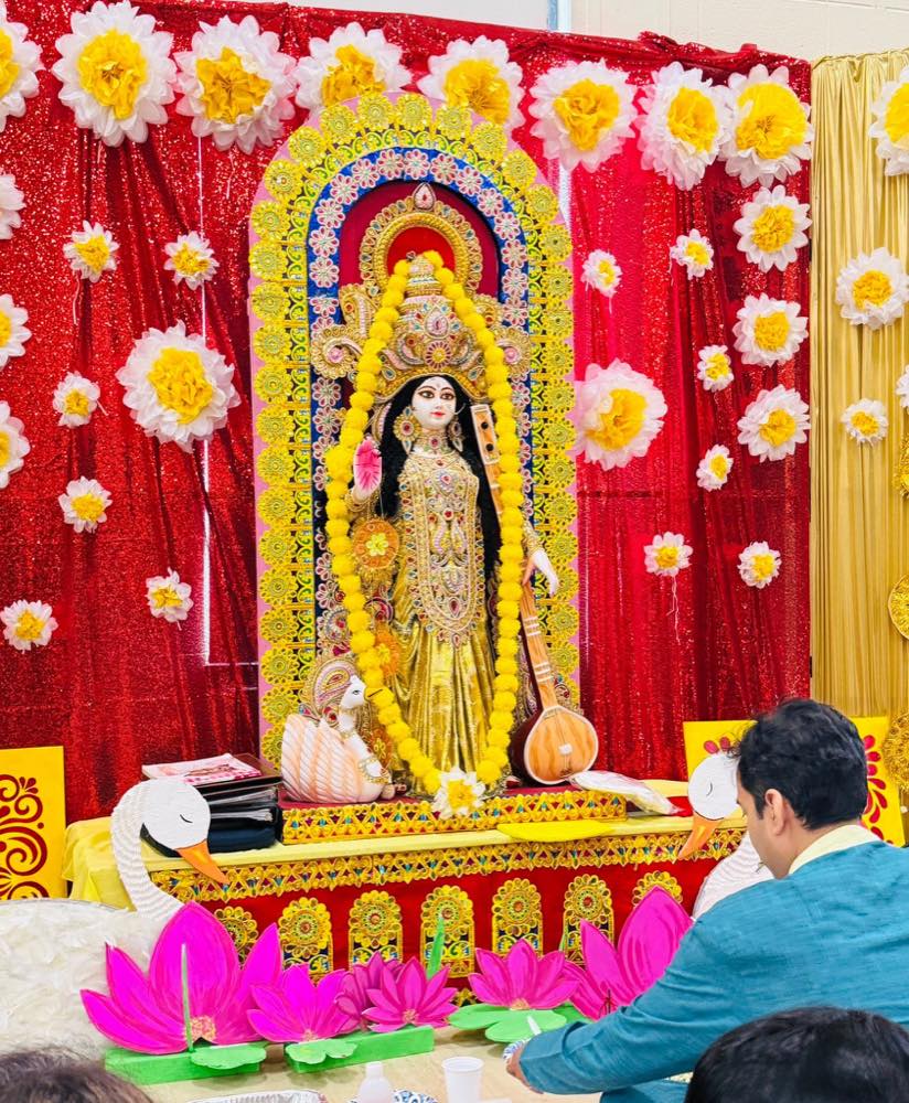 Saraswati Puja altar decorated with marigold garlands and paper flowers